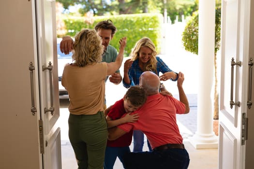 Rear view of caucasian senior couple hugging their family at the entrance of the house. family, love and togetherness concept, unaltered.