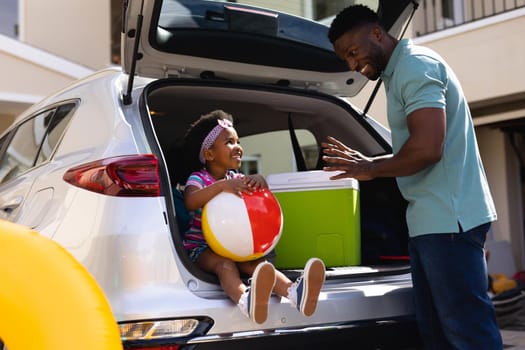 African american father talking to daughter sitting in the back of the car. family trip and vacation concept, unaltered.