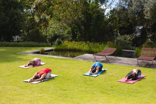 Men and women practicing yoga on exercise mats in public park on sunny day. healthy lifestyle and body care.