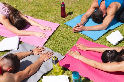 Men and women practicing yoga on exercise mats in park. yoga, healthy lifestyle and body care.