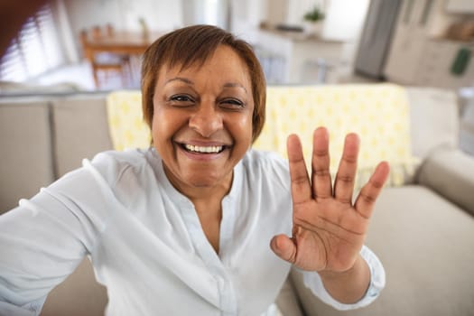 Happy african american senior woman waving hand during video call at home. lifestyle and communication.