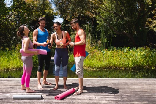 Cheerful men and women with healthy drinks standing in park post workout. healthy lifestyle, drink and fitness.