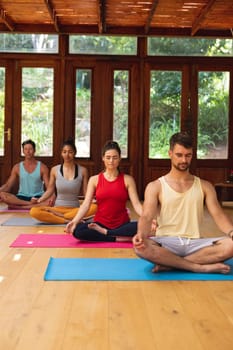 Men and women meditating while sitting on exercise mats at health club. healthy lifestyle, fitness and yoga.