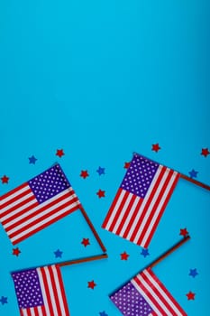 Usa flag sticks with star shape confetti by copy space on blue background. patriotism and identity.