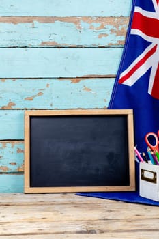 Blank writing slate by australian flag and desk organizer against old wooden wall with copy space. independence day, national flag and patriotism.