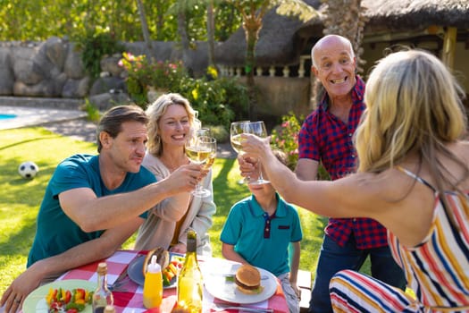 Cheerful caucasian three generation family toasting drinks in the garden. family, togetherness and weekend lifestyle concept, unaltered.