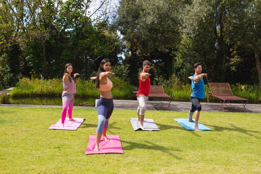 Female instructor teaching exercise to men and woman in public park. healthy lifestyle and body care.