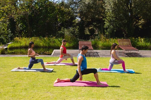 Men and women with practicing yoga on exercise mats in park on sunny day. healthy lifestyle and body care.