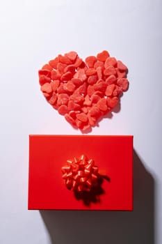 Overhead view of heart shaped red candies and gift box on white background, copy space. valentine's day, food and love concept.
