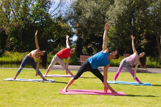 Men and women practicing exercising in public park on sunny day. yoga, healthy lifestyle and body care.