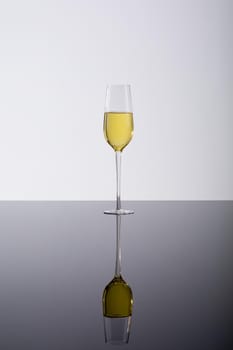 Closeup of champagne flute with reflection on glass table, drink against white background. celebratory party drink with copy space.