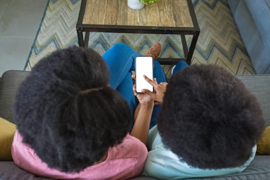 Teenage girl pointing at blank screen while teaching mother to use smart phone at home, copy space. wireless technology, lifestyle, family and advertising concept.
