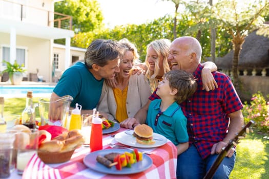 Cheerful caucasian three generational family laughing while sitting together in garden. family, togetherness and weekend lifestyle concept, unaltered.