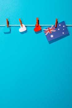 Australia flag and heart shapes hanging on clothesline with copy space against blue background. patriotism, symbol and identity.