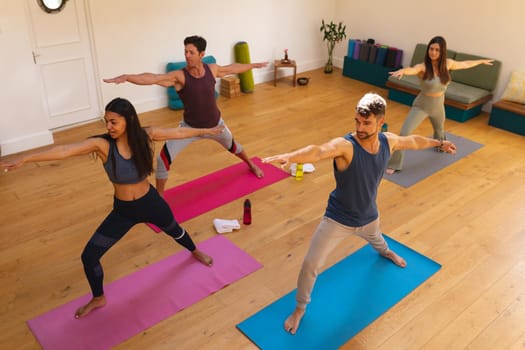 High angle view of multiracial women and men exercising during yoga session in yoga studio. fitness, yoga and healthy lifestyle.
