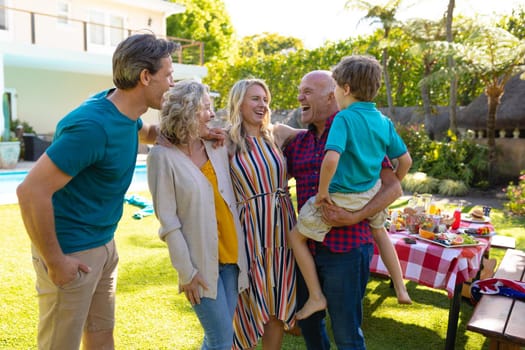 Cheerful caucasian family laughing while standing with arm around in backyard. unaltered, family, enjoyment, lifestyle and leisure activity.