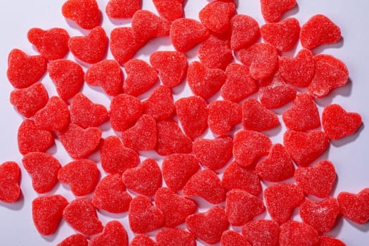 Overhead view of heart shaped red candies on white background, copy space. valentine's day, food and love concept.