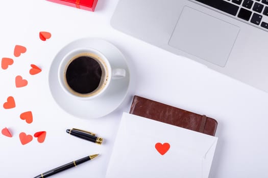 Overhead view of black coffee with love letter, fountain pen, laptop on white background, copy space. valentine's day, drink and love concept.