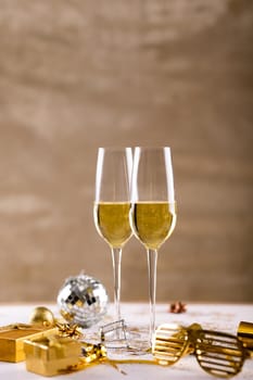 Closeup of champagne flutes by golden novelty glasses and gift boxes on table. celebration and party with copy space.