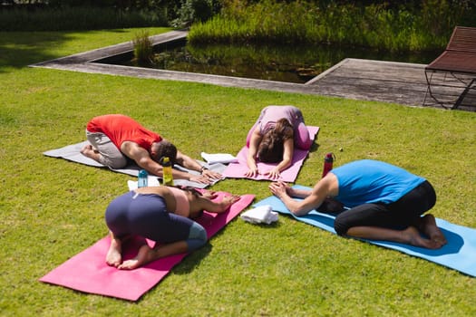 Men and women practicing yoga on exercise mats in park on sunny day. yoga, healthy lifestyle and body care.