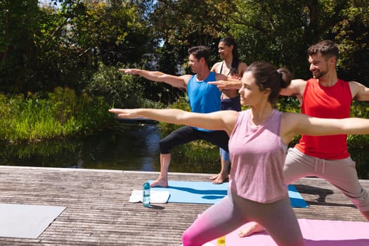 Female yoga instructor assisting men and woman during exercise session at park. healthy lifestyle and body care.