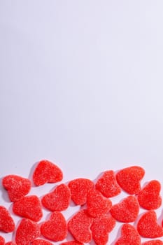 Overhead view of heart shaped red candies on white background, copy space. valentine's day, food and love concept.