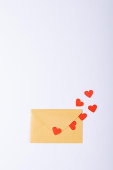 Overhead view of red hearts coming out from yellow envelope with copy space over white background. valentine's day and love concept.