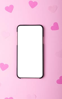 Directly above shot of smart phone with copy space and heart shaped papers on pink background. valentine's day, wireless technology and love concept.