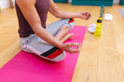 Low section of caucasian man meditating on exercise mat in yoga studio. fitness, yoga and healthy lifestyle.