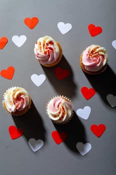 Overhead view of cupcakes and heart shaped decoration isolated on gray background, copy space. valentine's day, food and love concept.