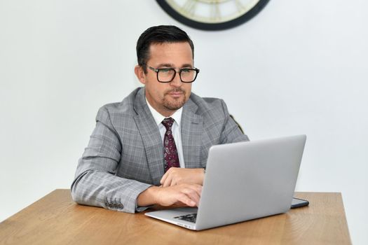 Mature man with glasses works at the laptop
