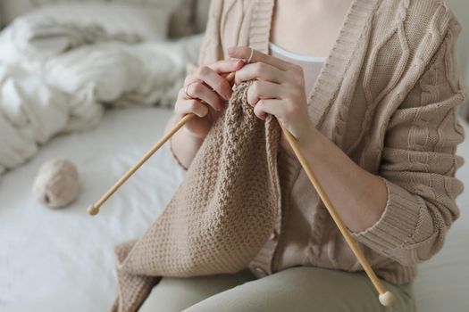 Women's hands knitting from woolen beige yarn