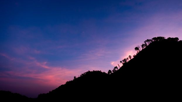 Beautiful landscape silhouette on the mountain peak during sunset with warm sunlight and dramatic sky.