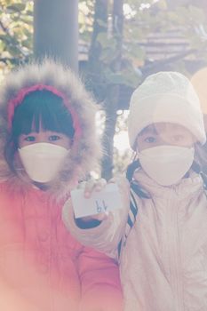 Children in protective face mask and winter clothes sit and wait to prepare for the hiking in nature with family. Learning activities and exploring nature on vacation. a new normal lifestyle.