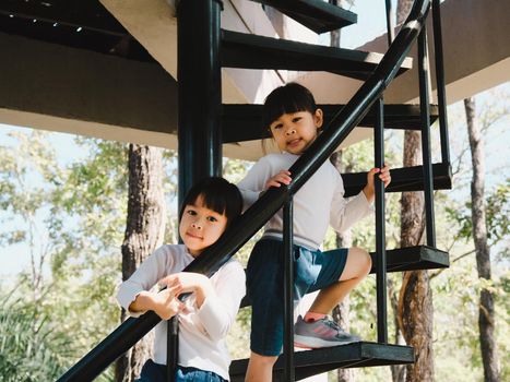 Two little girls climbed the stairs to the tower in the playground. Family outdoor recreational activity.