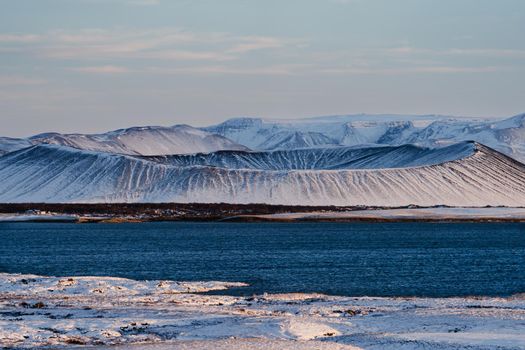 Volcano crater over the lake covered by snow in Myvatn lake, Iceland