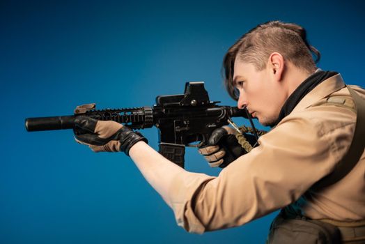 male special agent soldier in a bulletproof vest with an automatic rifle on a blue background