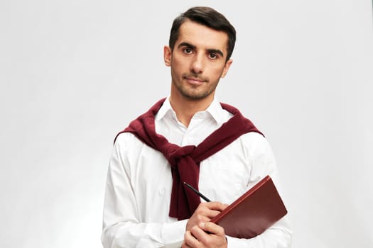 handsome businessman in a white shirt sweater on the shoulders notebook posing business and office concept. High quality photo