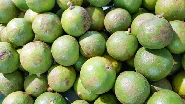 Many green limes are put on the shelves for sale.