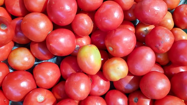 A large number of red tomatoes are placed on the shelves in the department store.