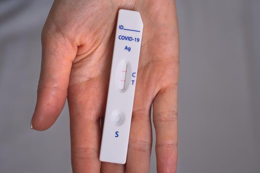 Woman hand holding rapid covid antigen test or express covid test with positive covid-19 result. High quality photo