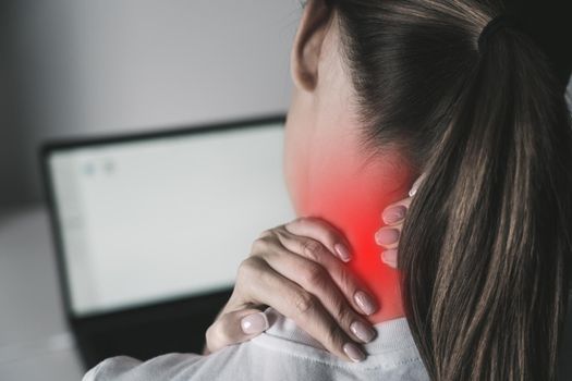 Woman suffering from neck pain after working on laptop. High quality photo