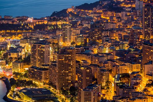 Aerial view of Monaco - Monte-Carlo at dusk, cityscape with night illumination, mountain, skyscrapers, mediterranean sea. High quality photo