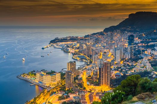 Aerial view of Monaco - Monte-Carlo at dusk, cityscape with night illumination, mountain, skyscrapers, mediterranean sea. High quality photo