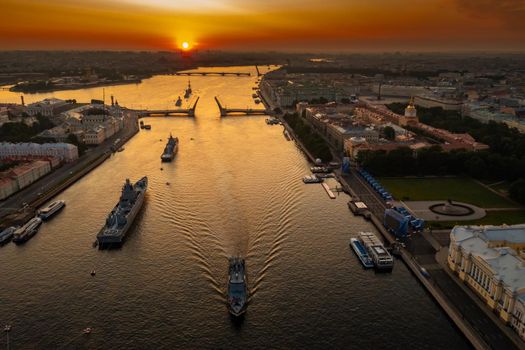 Aerial landscape with warships in the Neva River before the holiday of the Russian Navy at early morning, warships pass under a raised drawbridge, the latest cruisers among landmarks, Palace bridge. High quality photo