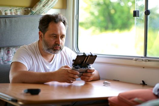 a man controls a drone from the window of a motorhome