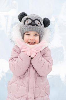little girl in a knitted hat and scarf and ice sculptures