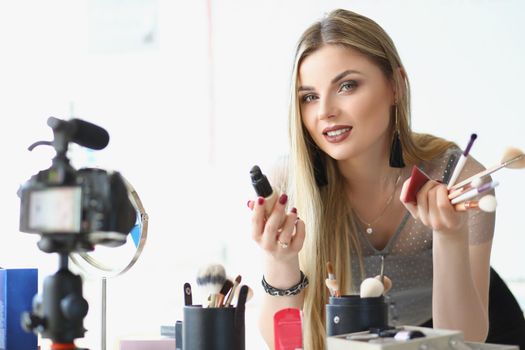 Portrait of charming beautiful young woman present beauty products for facial makeup on camera. Blogger tell about makeup art. Beauty, mua, channel concept