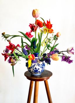 Home decor and the art of arranging bouquets. Bouquet of colorful garden flowers isolated on white background. The composition includes tulips, daffodils, muscari, lunaria, fritillaria and hellebore