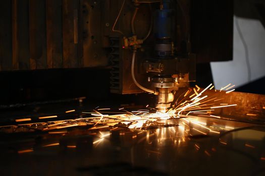 Close-up of machine head and metal processing laser metal, neon sparks fly out of it. Cutting machine and metal plate. Manufacturing, production concept